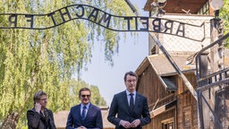 Ministerpräsident Wüst steht mit Anderen in Auschwitz unter dem Schriftzug "Arbeit macht frei"