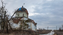 Ukraine-Krieg: Eine zerstörte Kirche in der Region Charkiw, ein Teil des Doms ist mit einer blauen Plane abgedeckt.
