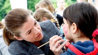 Anke Engelke schminkt ein Kind