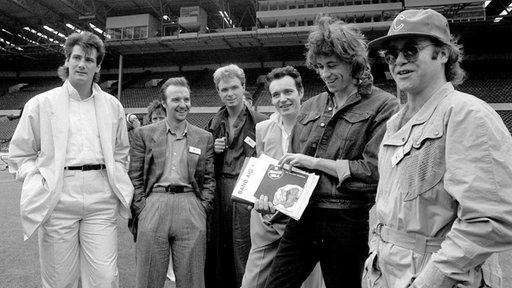 Bob Geldof umringt von Tony Hadley, Midge Ure, Gary Kemp, Adam Ant und Elton John (v.l.n.r.)