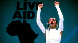 Sängerin Sade reckt während ihrer Performance beim Live-Aid-Konzert 1985 beide Arme in die Höhe