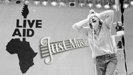 Bob Geldorf vor dem Live Aid Logo