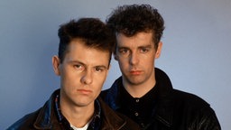 Chris Lowe und Neil Tennant, die Mitglieder Pet Shop Boys, posieren 1986 mit ernster Miene und Lederjacke für ein Porträtfoto
