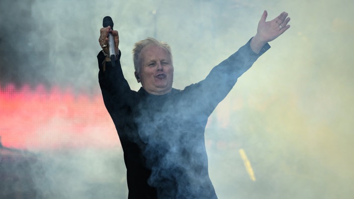 Sänger Herbert Grönemeyer steht beim Auftakt der Tournee 40 Jahre "4630 Bochum" 2024 im Dresdner Rudolf-Harbig-Stadion auf der Bühne und reckt die Arme in die Höhe