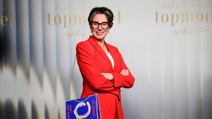 Ildikó von Kürthy bei der Kino-Preview zur 21. Staffel "Germany·s Next Topmodel" im Zoo Palast in Berlin. Sie trägt einen roten Blazer und eine auffallende, blaue Handtasche, die wie ein Buch aussieht und das Cover ihres neuen Buchs "Alt genug" abbildet. 