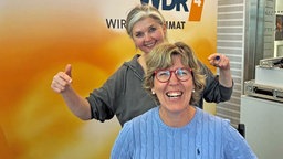 Katrin Iskam sitzt auf einem Stuhl im WDR 4-STudio, hinter ihr steht Heike Knispel