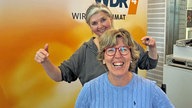 Katrin Iskam sitzt auf einem Stuhl im WDR 4-STudio, hinter ihr steht Heike Knispel