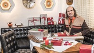Guildo Horn sitzt an einem Tisch umringt von Geschenken und Geschenkpapier