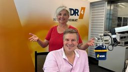 Krimiautor Michael Kobr sitzt auf einem Stuhl, hinter ihm steht Heike Knispel im WDR 4 Studio.