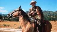 Der US-amerikanische Schauspieler Lorne Greene reitet in einer Szene der beliebten Western-Serie "Bonanza" als Familienoberhaupt "Ben Cartwright" auf einem Pferd