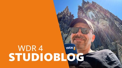 Lokalzeitreporter Peter Schultz steht mit Sonnenbrille und WDR 4-Mikro bei 35 Grad vor dem Kölner Dom