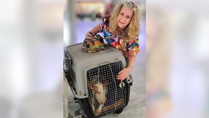 Anke Reichenauer am Flughafen mit einem Hund im Transport-Käfig