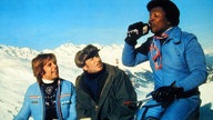 Thomas Fritsch, Klaus Schwarzkopf und Roberto Blanco trinken etwas vor einer alpinen Kulisse
