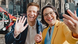 Bastian Bender und Katharina te Uhle machen ein Selfie vor dem Kölner Dom