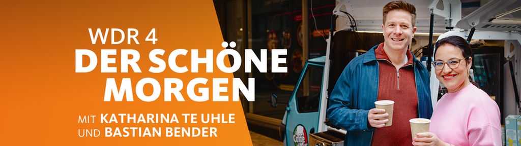 Zwei Personen in Straßenkleidung stehen mit einem Kaffeebecher in der Hand vor einem Kaffeewagen im städtischen Umfeld