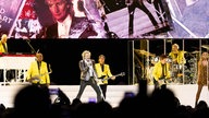 Rod Stewart singt auf einer Bühne, neben ihm spielt seine Band