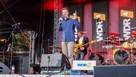 WDR 4-Moderator Bastian Bender steht auf einer Bühne 