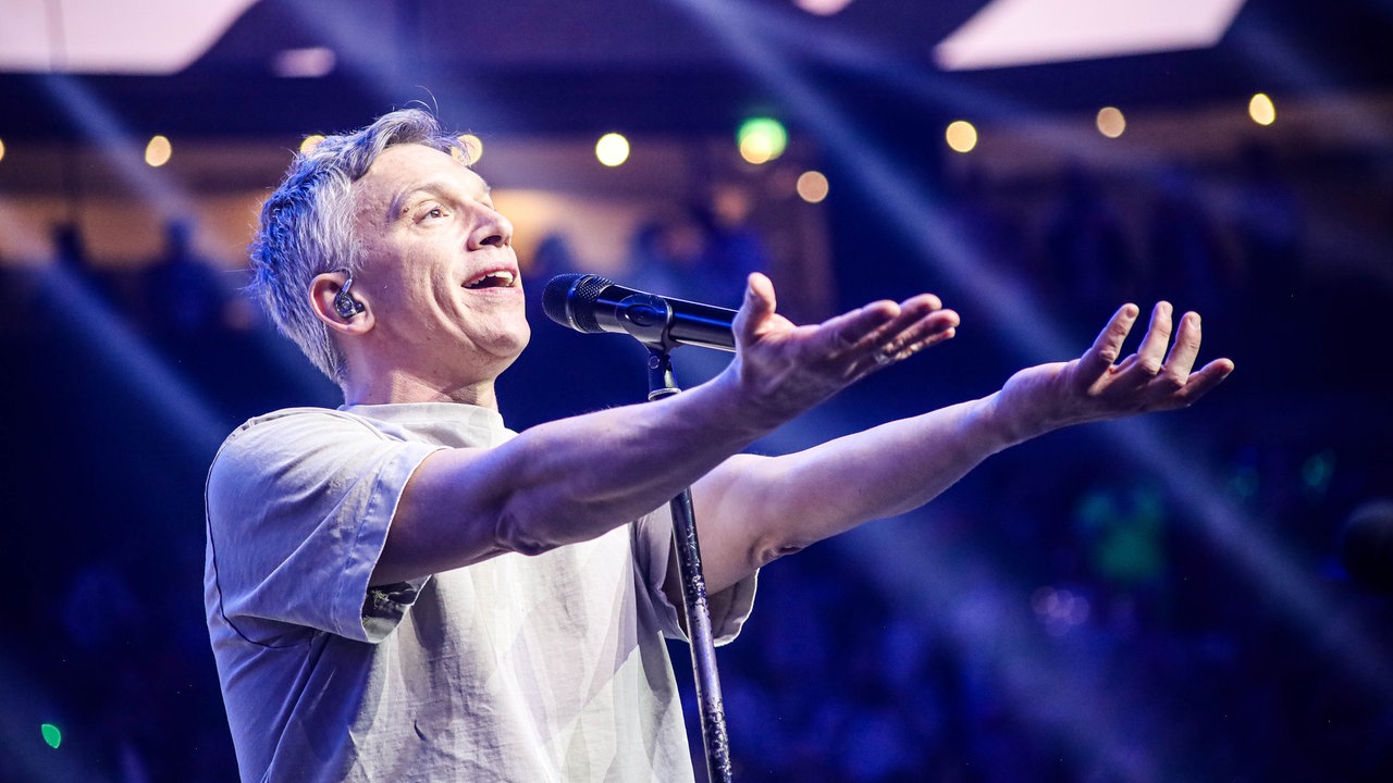 Lachende Köln Arena 2026: Der Sänger der Band Kasalla dirigiert mit seinen Armen zu den Klängen seiner Musik