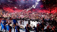 Lachende Köln Arena 2026: Ein Blick vom Oberrang hinter der Bühne. Der Elferrat steht auf Stühlen und tanzt hinter der Band mit