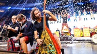 Lachende Köln Arena 2026: Stephan Brings von der Band Brings spielt die Gitarre, sein Bruder Peter feuert im Hintergrund eine Konfettikanone ab