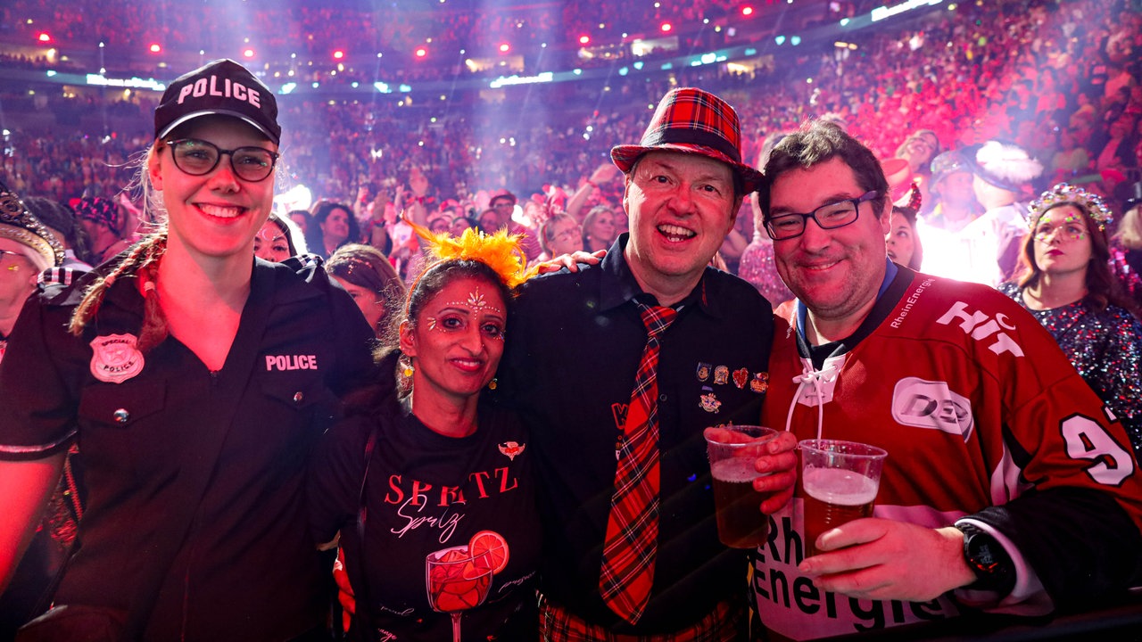 Lachende Köln Arena 2026: Vier verkleidete Fans schunkeln