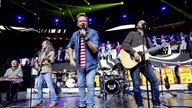 Lachende Köln Arena 2026: Die Band Bläck Fööss steht auf der Bühne. Der Frontmann singt mit einem Mikrofon vor dem Gesicht
