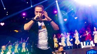 Lachende Köln Arena 2026: Die Band Höhner steht auf der Bühne. Der Sänger schaut in die Kamera und formt mit den Händen ein Herz