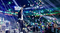 Lachende Köln Arena 2026: Von der Decke fliegen bunte Luftballons während die Band Höhner auf der Bühne singt 