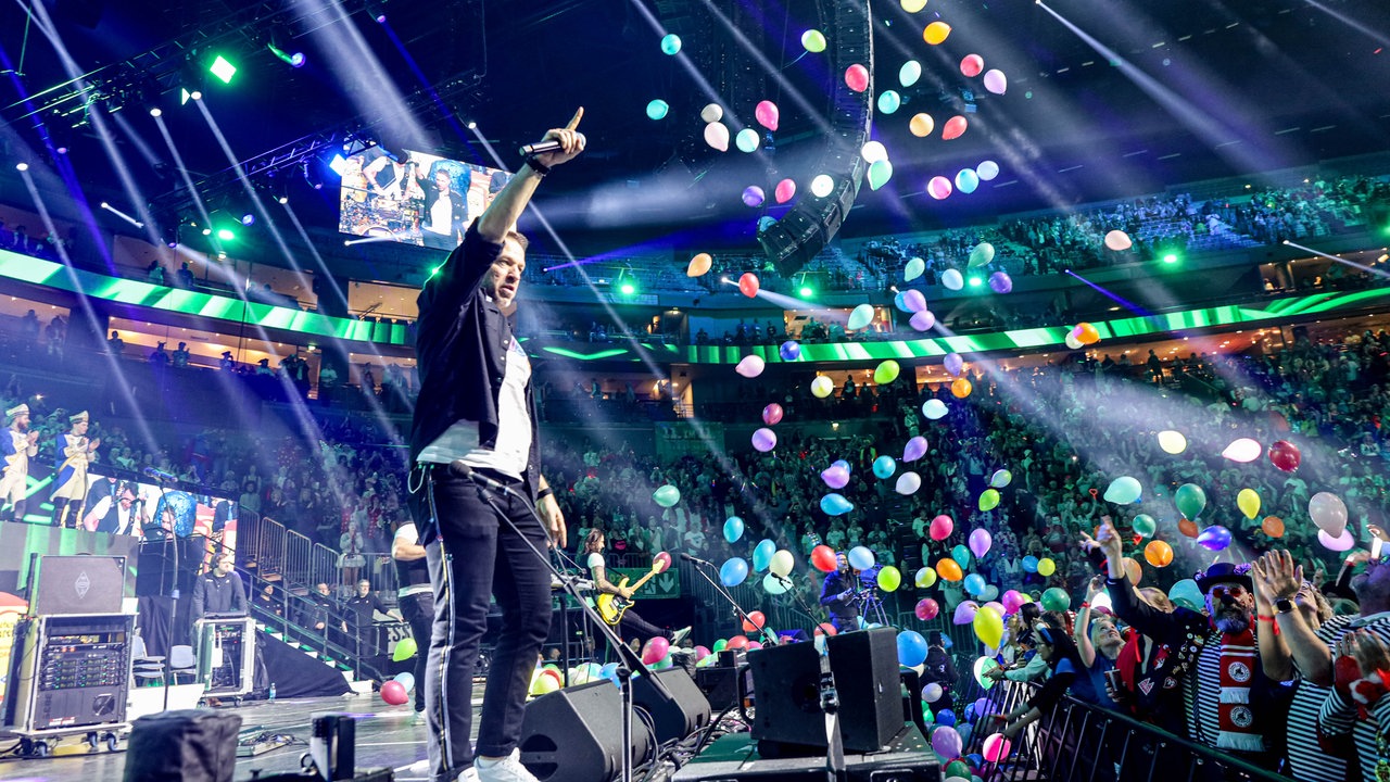 Lachende Köln Arena 2026: Von der Decke fliegen bunte Luftballons während die Band Höhner auf der Bühne singt 