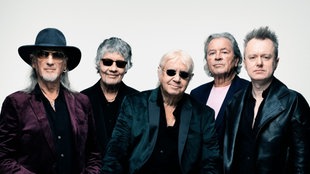 Die fünf Mitglieder der Band Deep Purple posieren nebeneinander vor einem weißen Hintergrund
