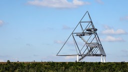 Das Tetraeder auf der Halde in Bottrop - ein tetraederförmiges Konstrukt aus Stahlrohren -  vor einem blauen Himmel mit vereinzelten Wolken. 