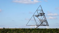 Das Tetraeder auf der Halde in Bottrop - ein tetraederförmiges Konstrukt aus Stahlrohren -  vor einem blauen Himmel mit vereinzelten Wolken. 