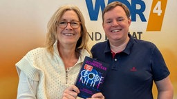 Das Buchcover "Code Null" von Florian Schwiecker wird von Ute Schneider und Mike Altwicker in die Kamera gehalten