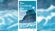 Buchcover: "Das Geschenk des Meeres" von Julia R. Kelly (Eine in blauen Tönen gemalte Küste mit einem Haus und stürmiger See)