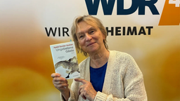 Elke Heidenreich steht im WDR 4 Studio mit dem Buch "Ungebetene Gäste" von Ayelet Gundar-Goshen in der Hand.