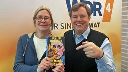 Buchcover: "Niemands Töchter" von Judith Hoersch (ein gemaltes Portrait einer braunhaarigen Frau mit einer Sonnenblume, die ein Teil ihres Gesichts verdeckt)in die Kamera halten von Ute Schneider und Mike Altwicker