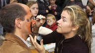 Anke Engelke malt ihrem Kollegen Christoph Maria Herbst 2004 in Köln beim Benefizrenntag zu Gunsten des Kölner Kinderschutzbunds das Gesucht bunt an