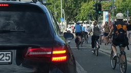 Ein Auto blinkt und lässt vor dem Rechtsabbiegen Fahrradfahrer passieren
