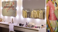 In einem Spiegel spiegelt sich eine Kleiderstange mit gelben Blazern wider, darunter befindet sich ein Schminktisch mit verschiedenen Beauty-Produkten.