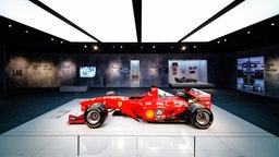 Ein Ausstellungsraum, in der Mitte steht ein roter Ferrari-Rennwagen. 