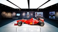 Ein Ausstellungsraum, in der Mitte steht ein roter Ferrari-Rennwagen. 