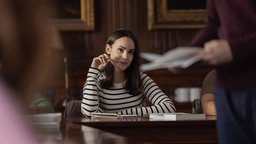 Szene aus dem Film "My Oxford Year": Schauspielerin Sofia Carson sitzt an einem Tisch in der Universität und schaut verträumt den Dozenten an