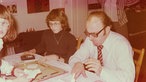70er Jahre: Eine Familie spielt an Weihnachten im Wohnzimmer Monopoly