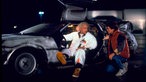 Szene aus dem Film "Zurück in die Zukunft": Schauspieler Michael J. Fox und Christopher Lloyd unterhalten sich vor dem Zeitreise-Auto