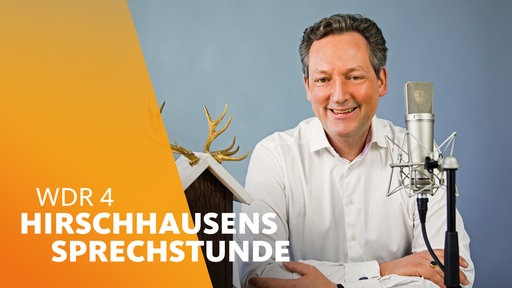 Dr. Eckart von Hirschhausen sitzt neben einem Vogelhaus und vor einem Mikrofon