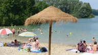 Badegäste sitzen am 22.07.2014 in Lippstadt (Nordrhein-Westfalen) am Ufer des Strandbads Alberssee.