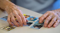 Eine ältere Dame spielt das Spiel "Memory" und legt Kartenpaare zusammen.