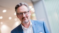 Porträtfoto von Dr. Eckart von Hirschhausen, aufgenommen im Vierscheibenhaus des WDR. Er trägt eine schwarze Brille, ein blaues Sacko mit buntem Einstecktuch und ein weißes Hemd. 