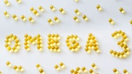 Omega-3 Fischöl-Kapseln als Schriftzug auf weißem Untergrund