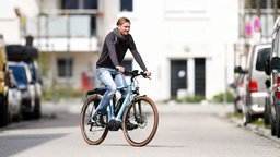 Ein Radfahrer ohne Helm fährt mit einem Pedelec auf der Straße 